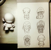 blank munny toy next to a sketchbook with 6 munny designs